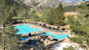 Un resort con varias piscinas, zonas de descanso y montañas al fondo.