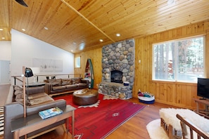 A wooden-paneled room with a stone fireplace, leather furniture, and a large window. - Gorgeous Tahoe Donner home with recreational activities  - near ski resorts (Truckee)
