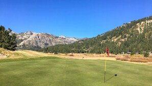 Camp de golf amb un pal de senyal, muntanyes al fons i cel serè.