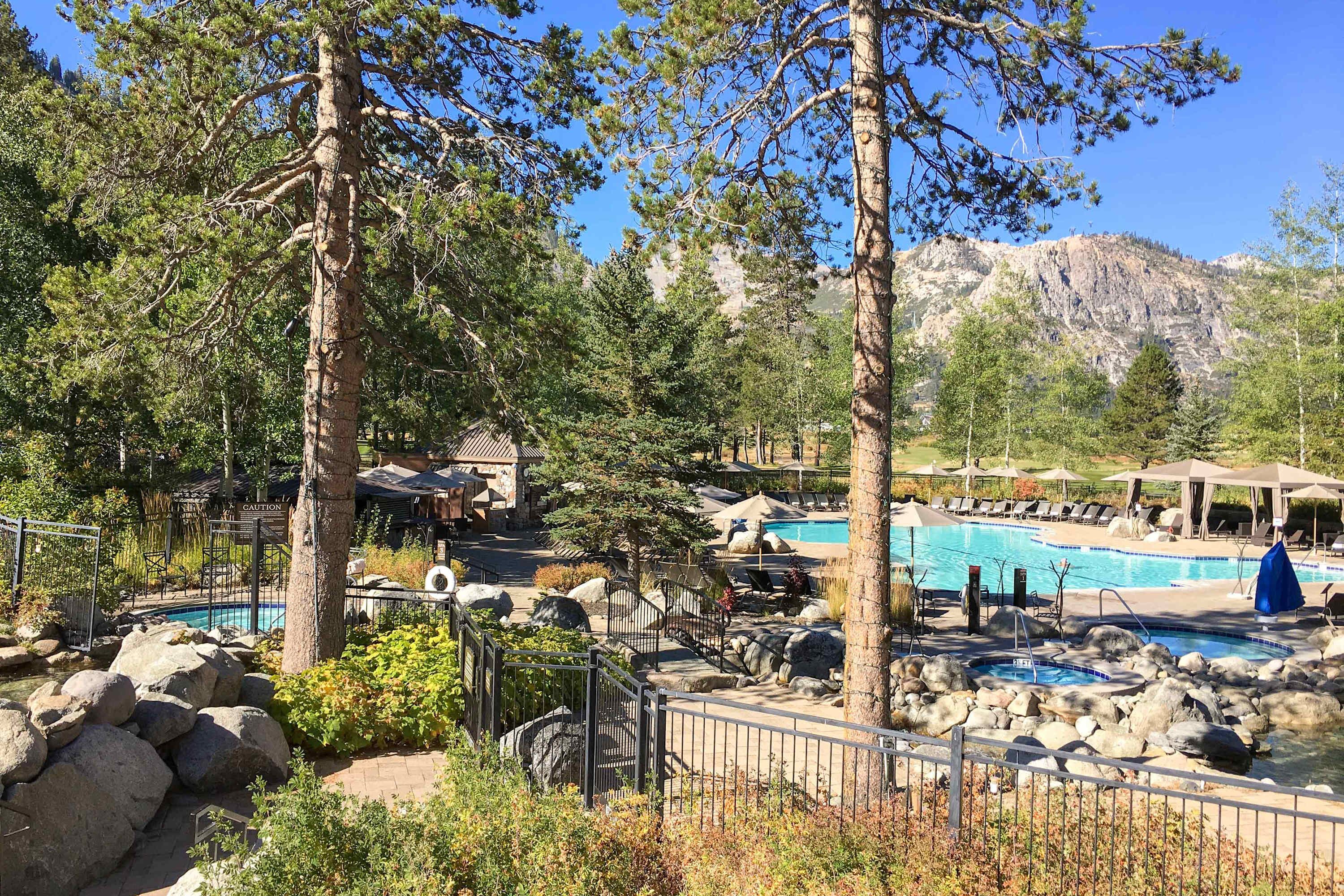 A resort with a pool area, surrounded by trees and mountains.