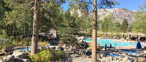 A resort with a pool area, surrounded by trees and mountains.
