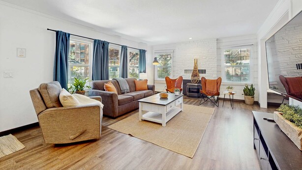 Ein modernes Wohnzimmer mit Sofa, Sessel, Couchtisch und Kamin.