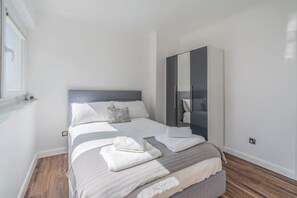 Quarto moderno com cama, um espelho grande e uma janela.
