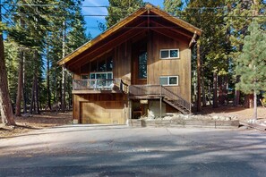 A two-story wooden cabin with a balcony, a garage, and a staircase leading to the upper level. - Cozy family cabin, pet friendly, a block from the water, close to ski, wifi (Carnelian Bay)