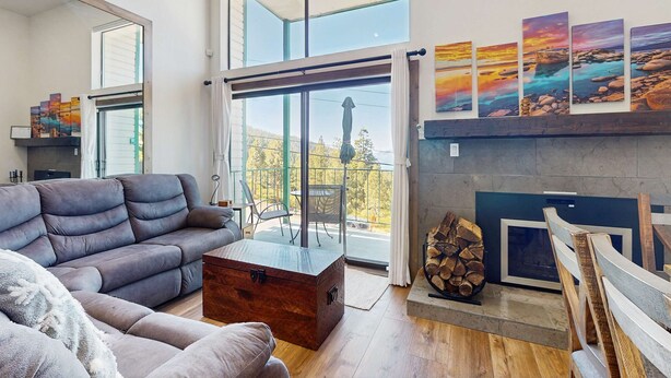 A modern living room with a sofa, a coffee table, a fireplace, and a balcony with a view. - Luxury Condo in Stateline: Lake & Mountain Views (Stateline)