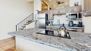 A modern kitchen with granite countertops, stainless steel appliances, and wooden cabinets. - Luxury Condo in Stateline: Lake & Mountain Views (Stateline)