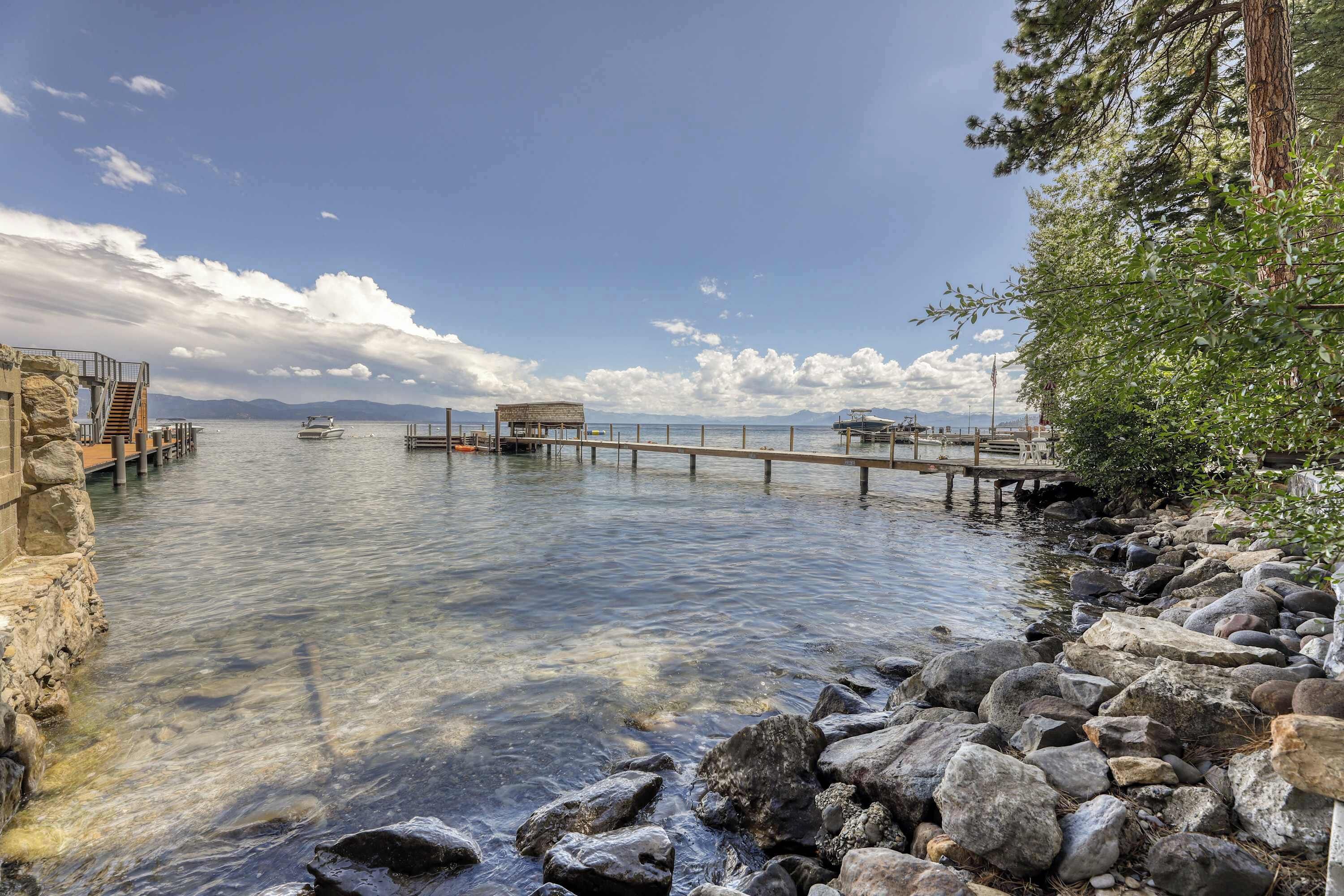 Ein ruhiges Ufer mit einer Steg, klarem Wasser und einer felsigen Küste.