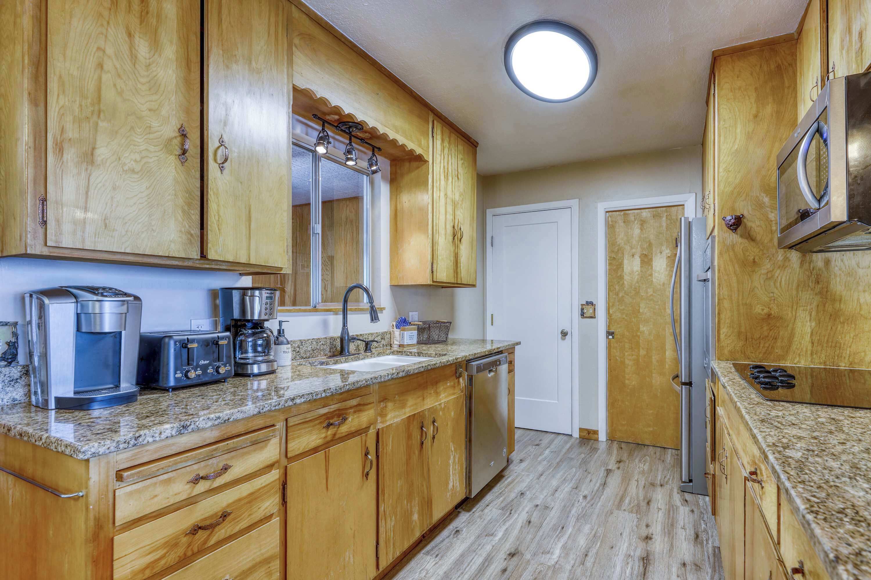 A kitchen with wooden cabinets, a stainless steel refrigerator, a coffee maker, and a toaster.