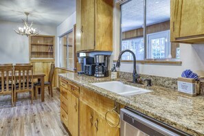 A kitchen with wooden cabinets, a granite countertop, a coffee maker, a sink, and a dishwasher. - Complimentary paddle boards and a relaxing sauna just steps from Lake Tahoe. (Carnelian Bay)