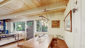 Una mesa de madera con sillas, un banco y vistas al exterior a través de amplios ventanales.