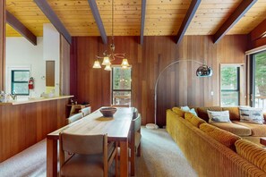 A wooden interior with a dining table, sofa, and a large window. - Serene home with fireplace, spacious deck, sauna, WiFi and nearby activities (Truckee)