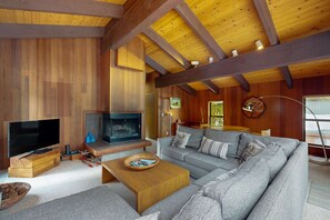 A cozy living room with a television, sofa, wooden coffee table, and a fireplace. - Serene home with fireplace, spacious deck, sauna, WiFi and nearby activities (Truckee)