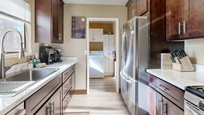 Una cocina con un refrigerador de acero inoxidable, una cafetera y un juego de cuchillos.