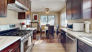 Una cocina con estufa, microondas y armarios.
