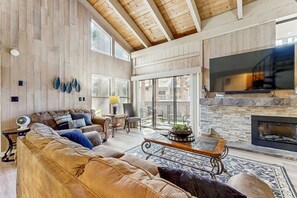 Ein geräumiges Wohnzimmer mit großem Fernseher, Kamin und bequemen Sitzgelegenheiten.