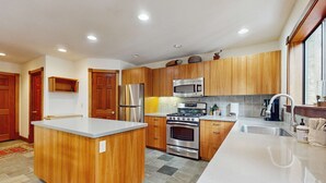 Una cocina moderna con armarios de madera, electrodomésticos de acero inoxidable, una isla central y un ventanal grande.