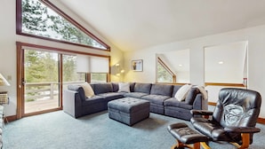 Una sala de estar moderna con un sofá seccional, un reposapiés, un sillón de cuero y una mecedora.