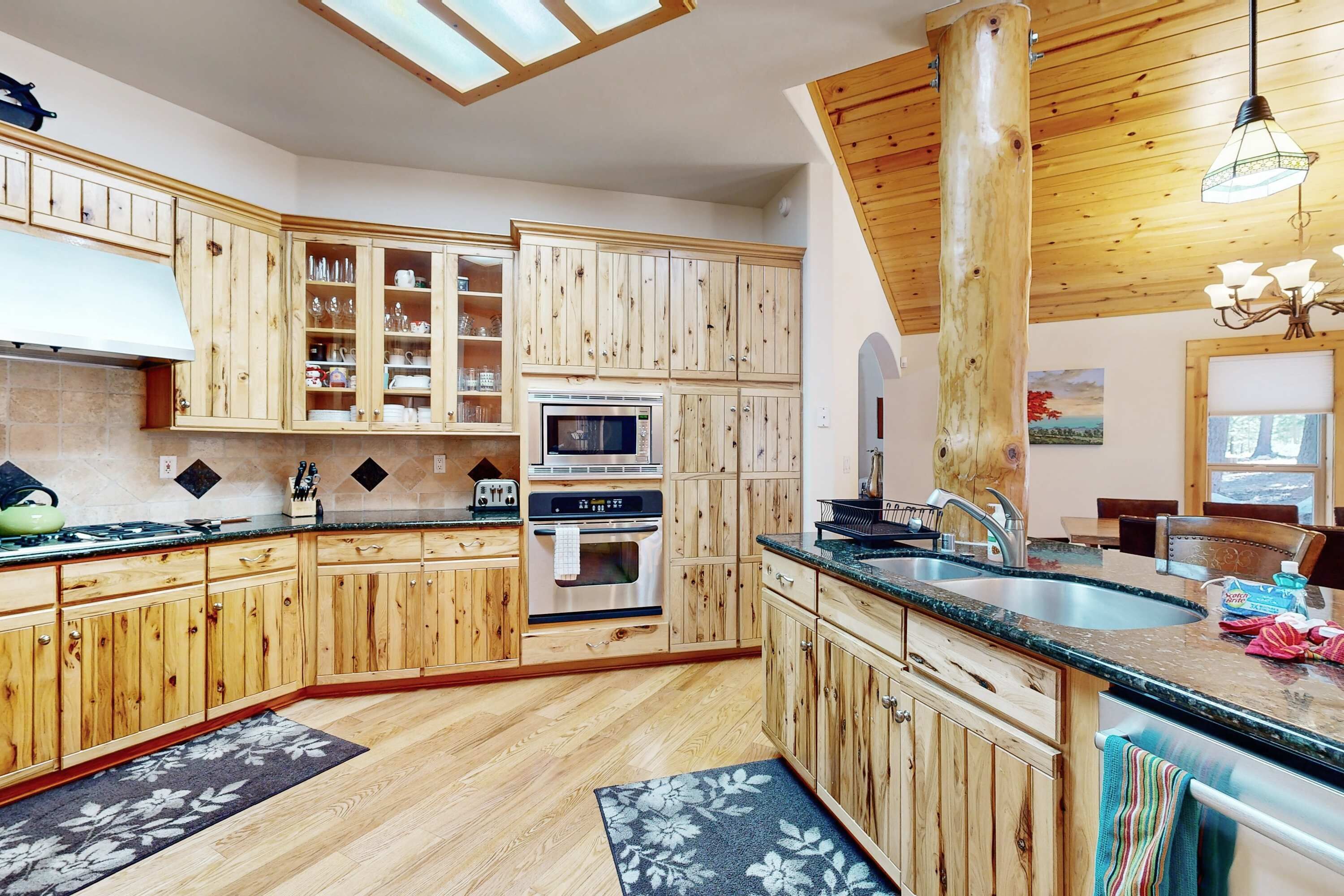 A kitchen with wooden cabinets, a microwave, an oven, a sink, and a chandelier.