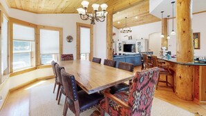 A dining area with a large wooden table, chairs, and a chandelier. - Wooded Luxury at Modern Tahoe Donner Retreat with Private Deck in the Pines (Truckee)