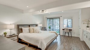 Quarto com cama, mesas de cabeceira, escrivaninha e uma cadeira.