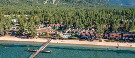 A coastal resort with a pier, beachfront villas, and a mountain backdrop.