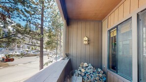 A wooden deck with a stack of firewood, a birdhouse, and a window. - Rustic mountain view condo w/ full kitchen - walk to lifts (Olympic Valley)