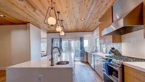 Une cuisine moderne avec un plafond en bois, des appareils en acier inoxydable et un grand îlot central.
