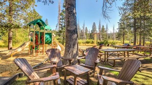 Ein Spielplatz mit Rutschen und ein Picknickbereich mit Adirondack-Stühlen und Picknicktischen.