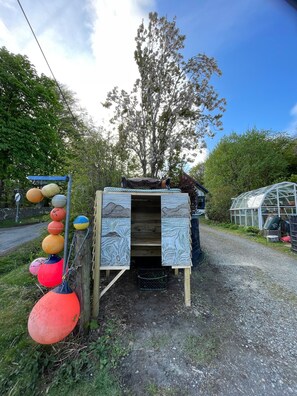 A wooden structure with a door, a metal fence with colorful balls, and a greenhouse in the background. - Room-charming Guest Room in the Beautifu (Isle of Mull)