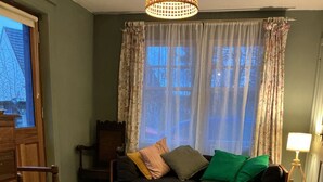 A living room with a sofa, a wooden chair, a lamp, and a view through a window. - Room-charming Guest Room in the Beautifu (Isle of Mull)