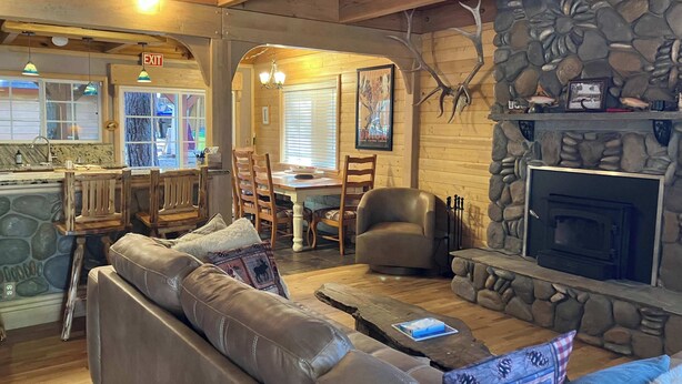 A cozy interior with a stone fireplace, wooden dining area, and a leather sofa. - Walkup Pines (South Lake Tahoe)