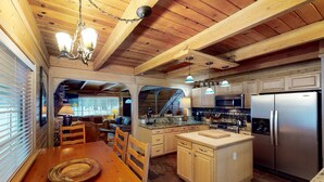 A wooden interior with a dining table, kitchen island, and built-in appliances. - Walkup Pines (South Lake Tahoe)