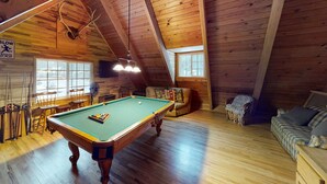 A wooden interior with a pool table, a sofa, and a fan. - Walkup Pines (South Lake Tahoe)