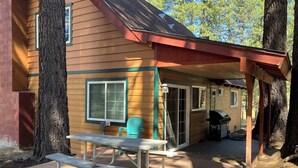 A wooden cabin with a covered patio area, a picnic table, and a grill. - Walkup Pines (South Lake Tahoe)