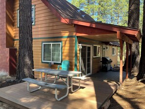 A wooden cabin with a covered porch, a picnic table, and a grill area. - Inviting home with pool table - near Heavenly & beaches (South Lake Tahoe)
