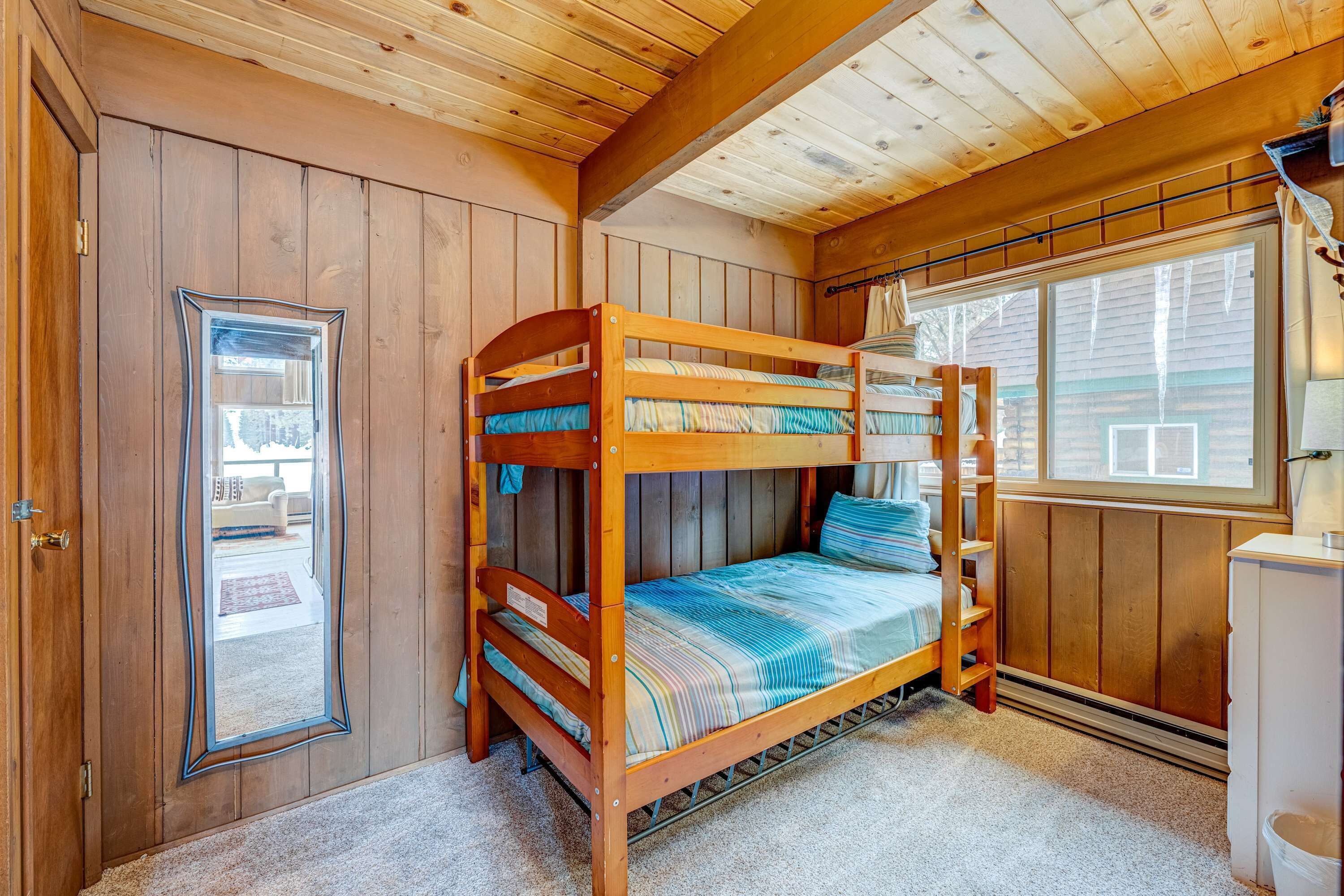 Dormitorio con literas, techo de madera, una ventana y un espejo en la pared.