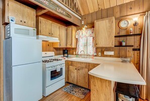 Una cocina con armarios de madera, microondas, estufa y pileta.