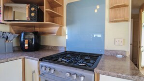 A compact kitchen with a gas stove, oven, and a built-in microwave. - Ocean Breeze Escape (Rochester)