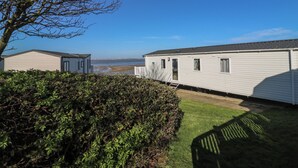 A mobile home with a garage, a small deck, and a view of the beach. - Ocean Breeze Escape (Rochester)