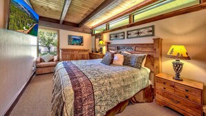 Ein Schlafzimmer mit einem großen Bett, einem Nachttisch mit Lampe, einem Schminktisch und einem Gemälde an der Wand.