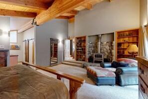 A cozy living room with a fireplace, a sofa, a bench, and a bookshelf. - Serene home with fireplace, wood stove, kitchen, W&D, hot tub, & gas grill (Truckee)