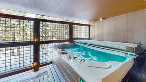 A hot tub with a wooden deck and a view of trees through a window. - Modern mountain home with private hot tub, deck, fireplace, & skiing nearby (Northstar - Truckee)