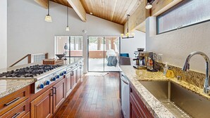 A kitchen with wooden cabinets, a granite countertop, a stainless steel sink, and a gas stove. - Modern mountain home with private hot tub, deck, fireplace, & skiing nearby (Northstar - Truckee)
