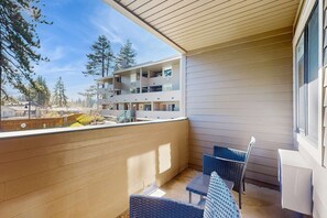 Ein Balkon mit Blick auf ein mehrstöckiges Gebäude, Gartenmöbel und ein Holzterrasse.