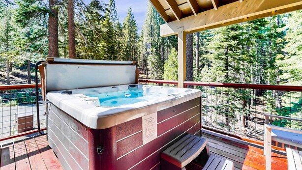 Ein Whirlpool auf einer Holzterrasse mit Blick auf einen Wald.