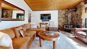 Un accogliente soggiorno con parete in pietra, soffitto in legno e camino.