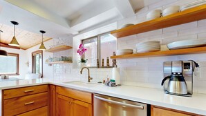 Una cucina con mobili in legno, una lavastoviglie in acciaio inossidabile, una macchina da caffè e una finestra con vista.
