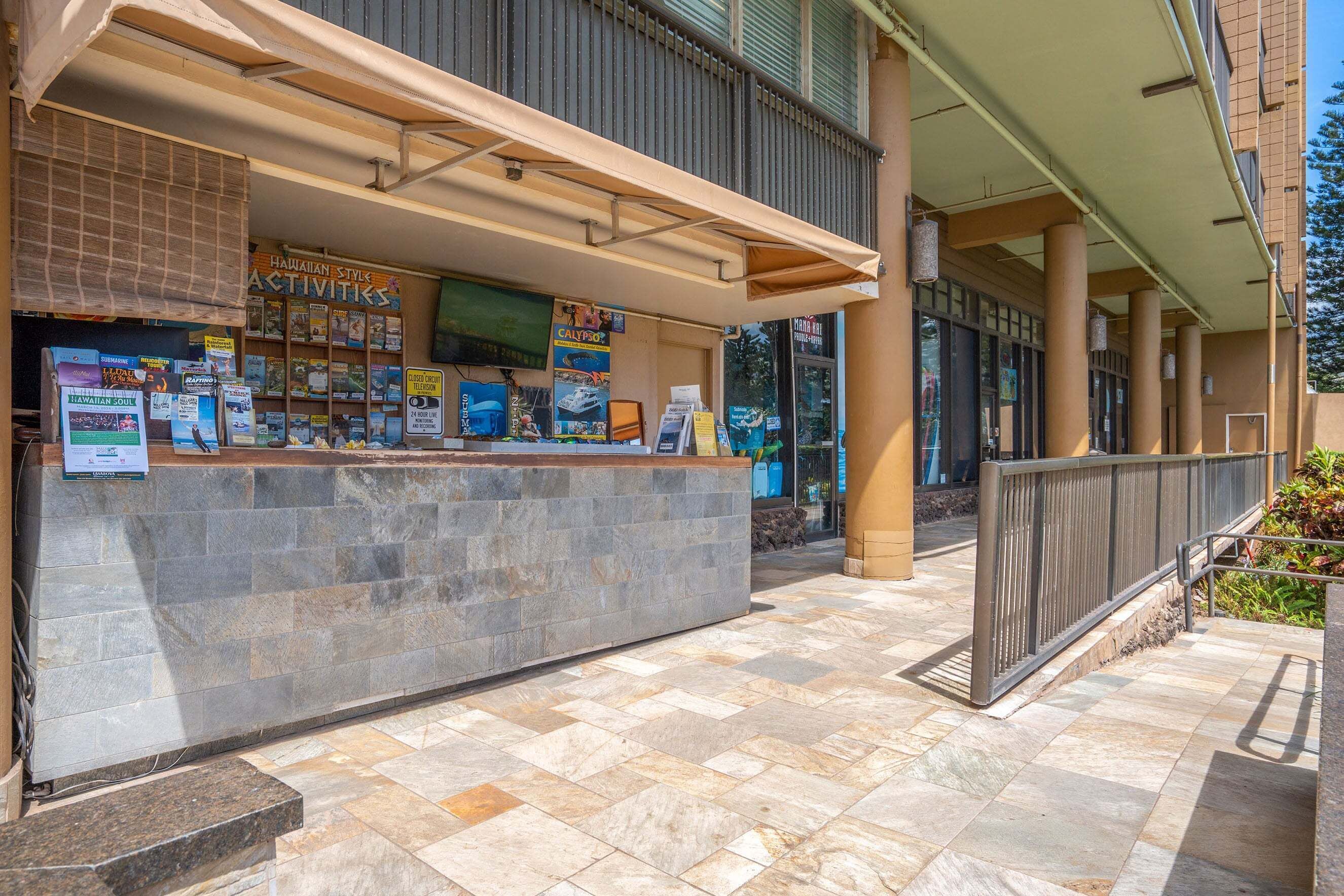 A reception area with a stone counter, a sign for 'Hawaiian Styles Activities', and a tiled floor.