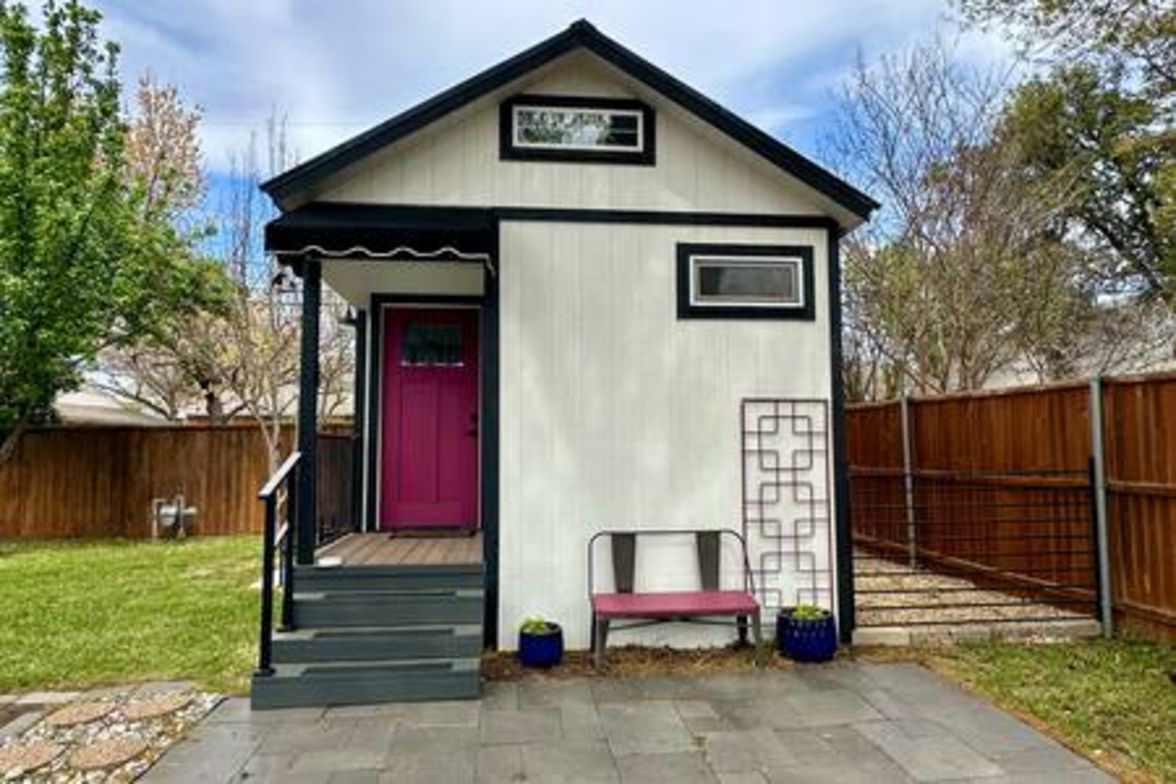 A small, single-story building with a red door and a sign above it.