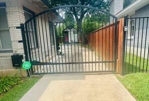 A gated entrance with a metal gate, a mailbox, and a small shed in the background. - New Cottage + Monthly + Fire Pit + Outdoor Kitchen (Dallas)
